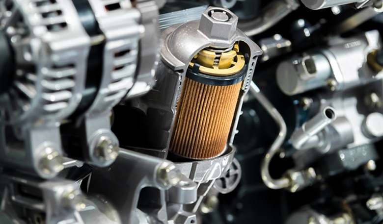 Oil filter within a car engine, showcasing its cylindrical shape and pleated paper design. Highlights the importance of regular engine maintenance.